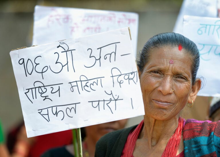 A woman holds a sign during a march celebrating International Women's Day on March 8, 2016, in Dhawa, a village in the Gorkha District of Nepal.