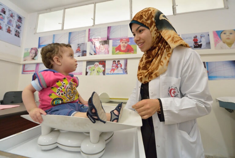 Nurse Asma El Shami carefully weighs a child in the pediatric department of Al Ahli Arab Hospital in Gaza City.