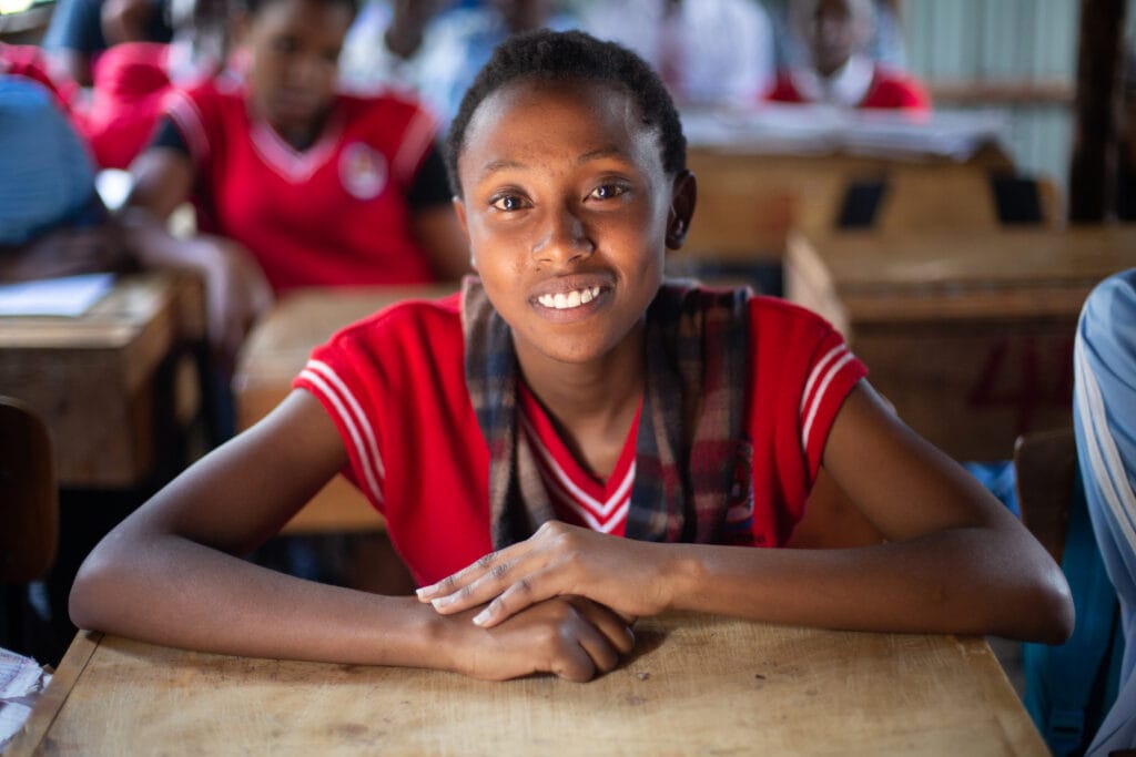 Young Kenyan girl in classroom smiling at the camera